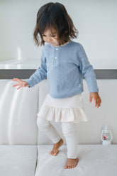 Toddler girl wearing Avauma milky white skirt leggings with subtle ruffle trim and a pastel top – cute and comfortable daily outfit